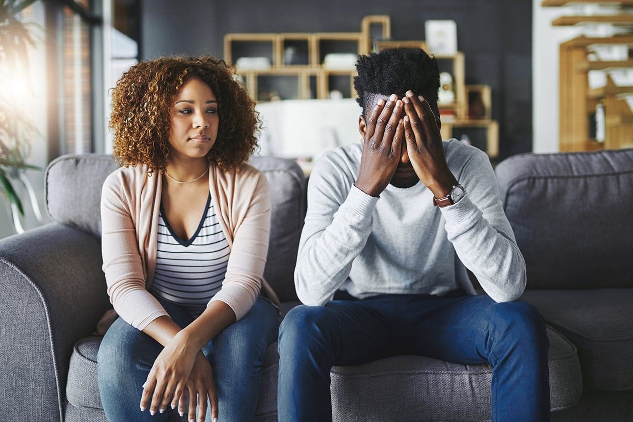 Couple sitting on a couch appearing distressed and disconnected, representing relationship challenges addressed in couples counseling.