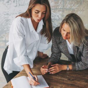 Two professionals discussing and writing notes together, representing executive coaching, career guidance, and professional development support.