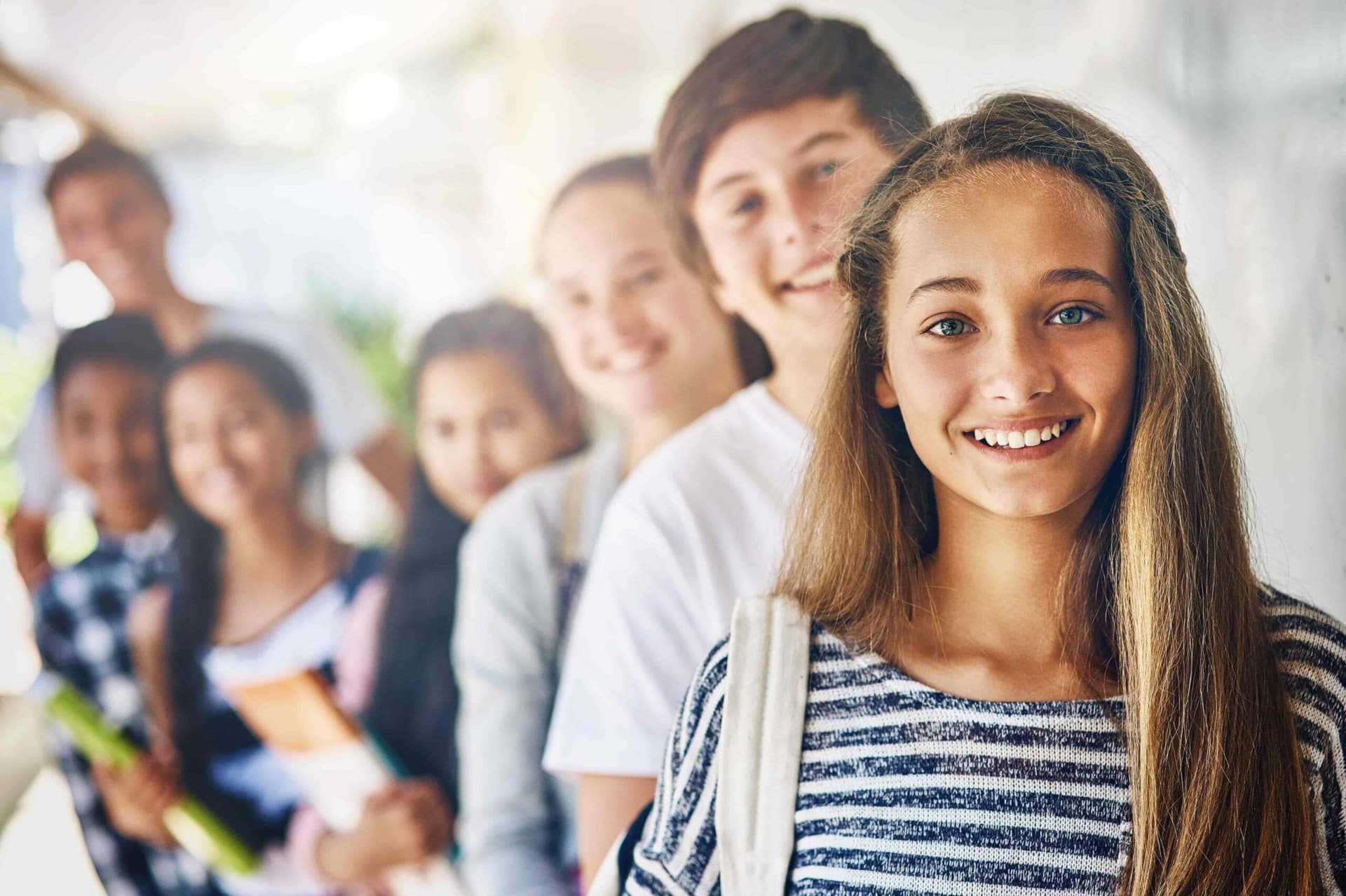 Group of smiling teenagers standing together, representing emotional support and guidance through teen counseling services.
