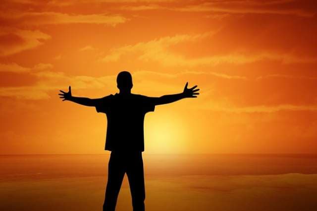 Silhouette of a teenager with arms outstretched at sunset, representing confidence, emotional growth, and self-discovery through teen counseling.